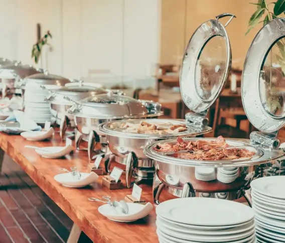 A long buffet table set with silver chafing dishes