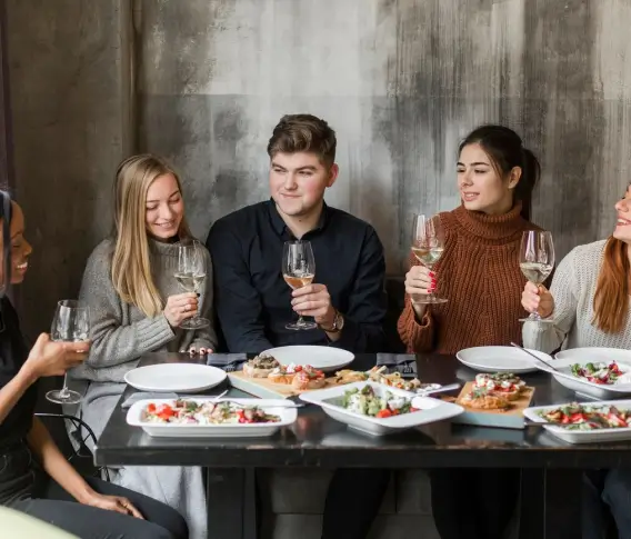 A group of friends toasting wine glasses at a restaurant table