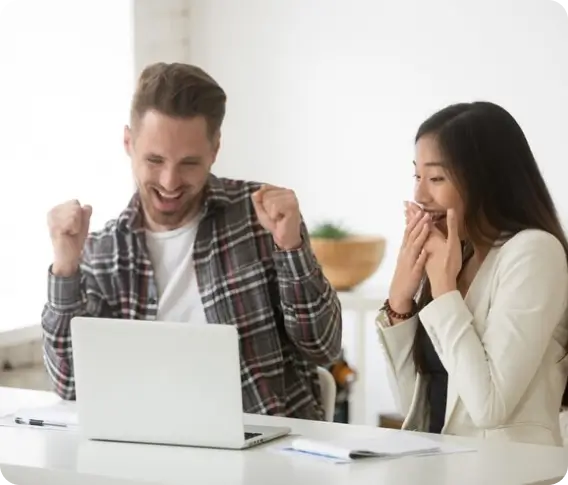 A couple celebrating in front of a laptop