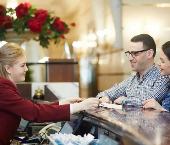 A host handing a card to seated guests at a restaurant counter